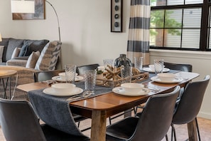 A dining area with a wooden table set for four, surrounded by chairs, with a view of the outside through a window. - Enjoy the Indoor Pool, Hot Tub and Sauna! Free Daily Attraction Tickets (Branson)