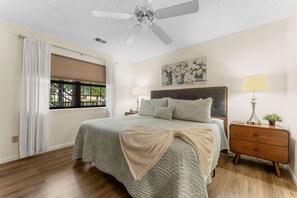 A bedroom with a bed, nightstands, a ceiling fan, a window with curtains, and a painting on the wall. - Enjoy the Indoor Pool, Hot Tub and Sauna! Free Daily Attraction Tickets (Branson)