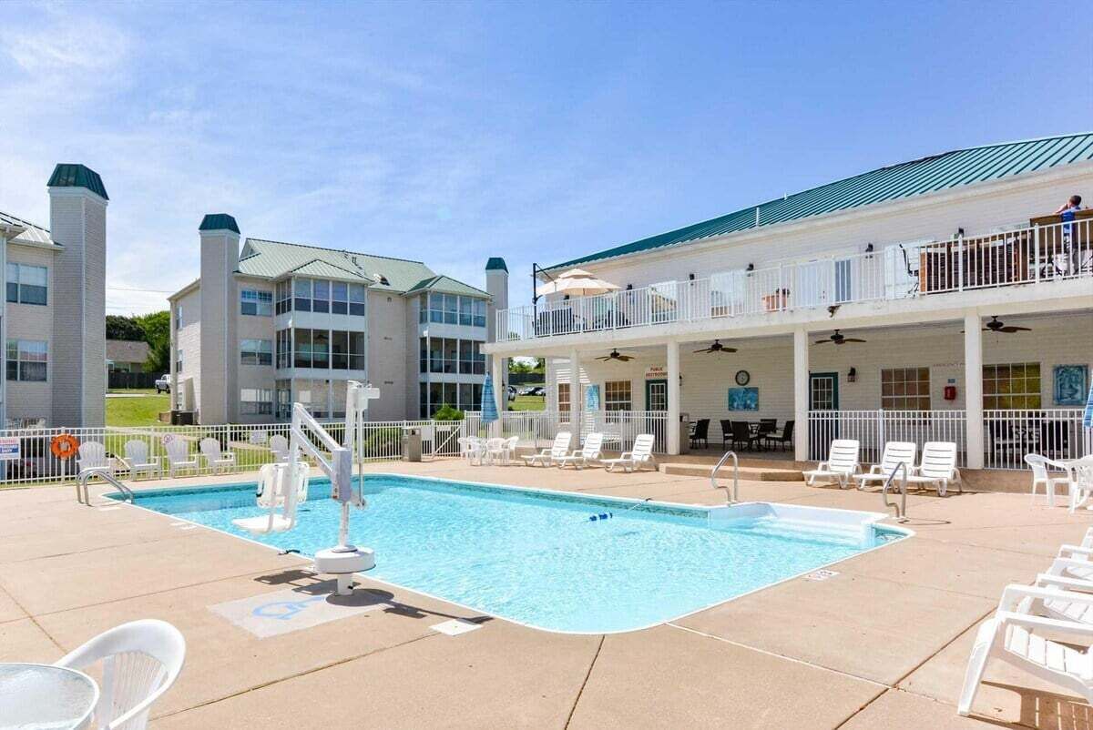 A swimming pool with lounge chairs and a covered area with tables and umbrellas.