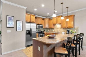 A kitchen with wooden cabinets, stainless steel appliances, and pendant lighting. - Table Rock Lake - Emerald Pointe - Walk In Condo w Lake and Pool Access (Hollister)