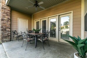 A covered patio with a table and chairs, a ceiling fan, and a potted plant. - Table Rock Lake - Emerald Pointe - Walk In Condo w Lake and Pool Access (Hollister)