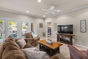 A living room with a sofa, armchairs, a coffee table, a TV, and a ceiling fan. - Table Rock Lake - Emerald Pointe - Walk In Condo w Lake and Pool Access- Free Daily Tickets (Hollister)