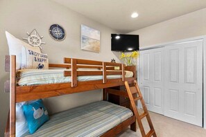 A bunk bed with a ladder, a wall clock, a compass, a framed picture, and a TV mounted on the wall. - Table Rock Lake - Emerald Pointe - Walk In Condo w Lake and Pool Access (Hollister)