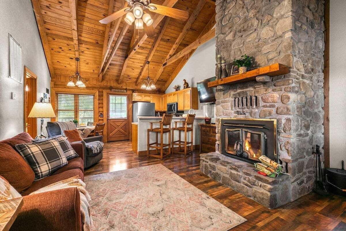Una sala de estar acogedora con chimenea, techo de madera y pared de piedra.