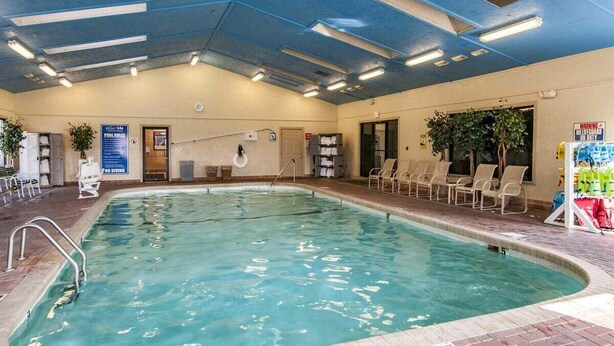 Una piscina interior amb superfície d'aigua cristal·lina, envoltada de gandules i un senyal de seguretat.