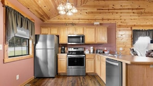 Cocina con armarios de madera, electrodomésticos de acero inoxidable y techo de madera.