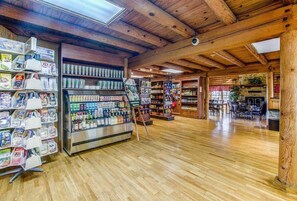 A wooden interior with a glass display case, shelves with various items, and a seating area.