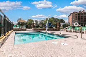 A swimming pool with a stone deck, lounge chairs, and a lifeguard stand.