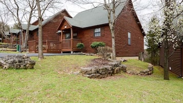 A row of log cabins with a porch and a stone retaining wall.