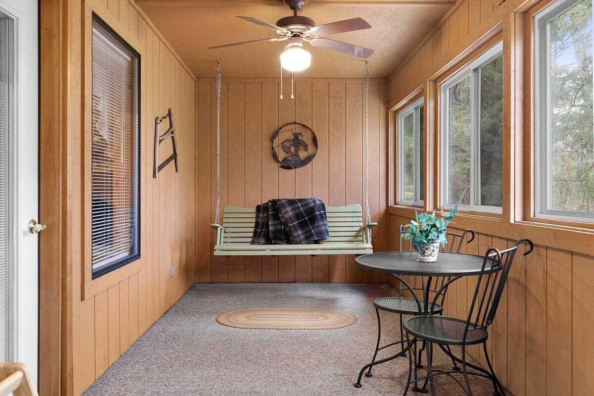 A wooden interior with a bench, a table with chairs, and a ceiling fan.