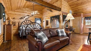 A cozy cabin interior with a leather sofa, wooden walls, and a ceiling fan.