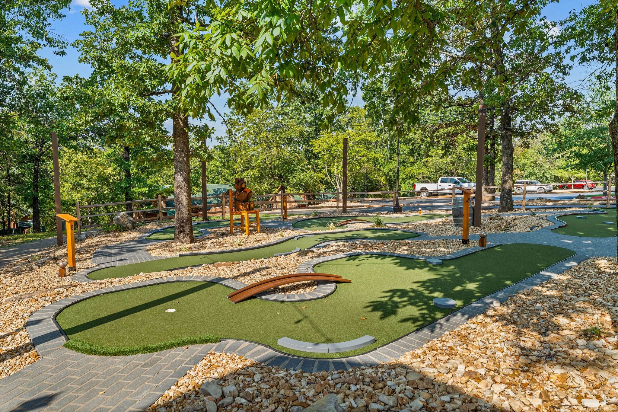 A miniature golf course with a putting green, sand traps, and a wooden bench.