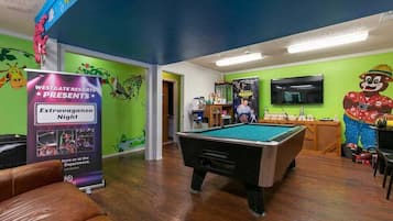 A pool table in a room with green walls and a poster advertising an event.