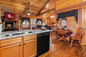 A cabin interior with a kitchen area, dining space, and a fireplace.