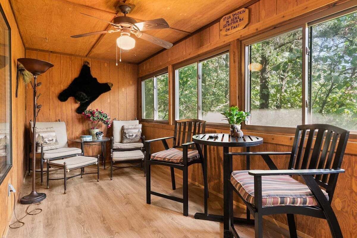 A wooden interior with a ceiling fan, large windows, and a mounted bear head.