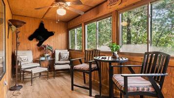 A wooden interior with a ceiling fan, large windows, and a mounted bear head.