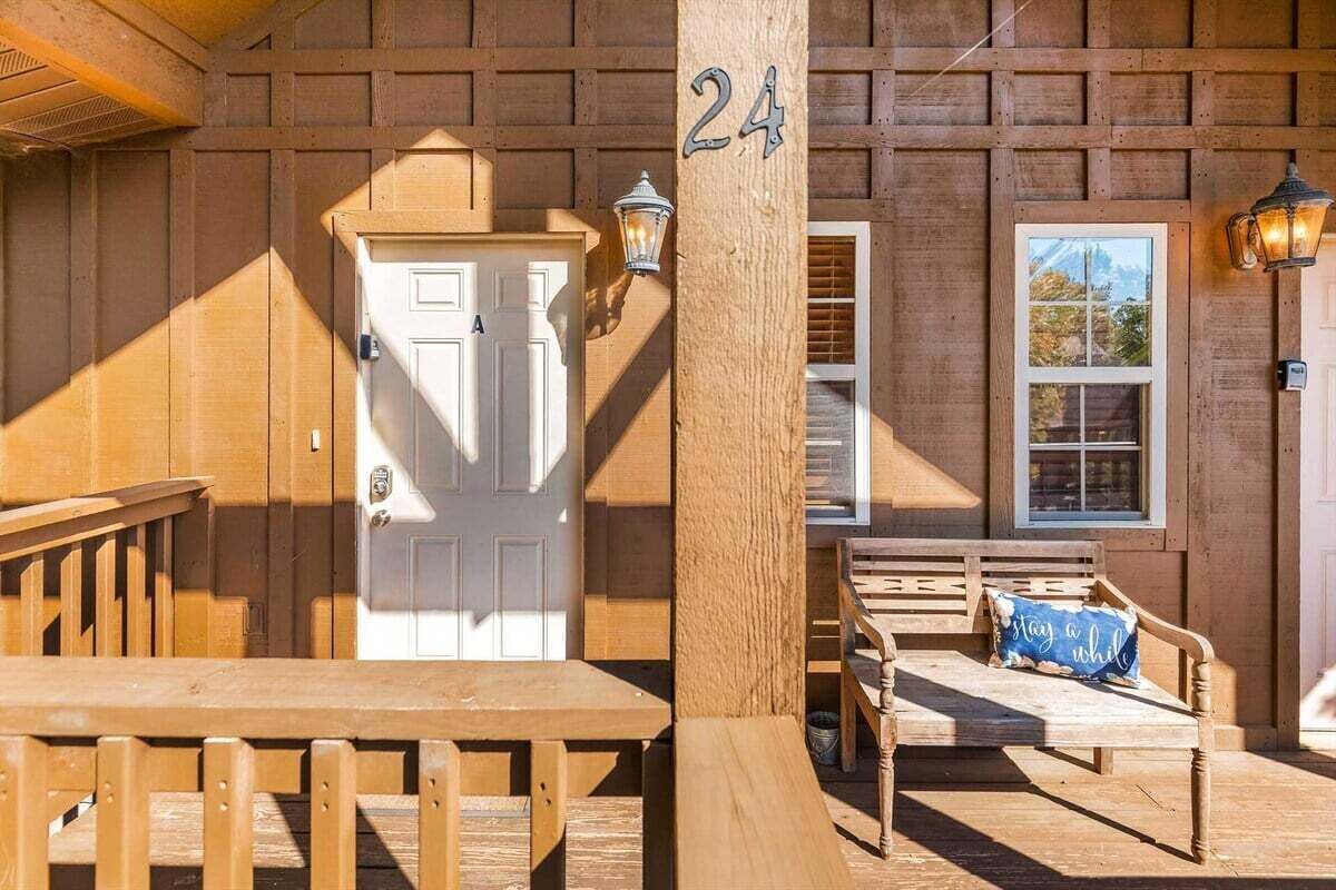 A wooden exterior with a door, a bench, and a number sign.