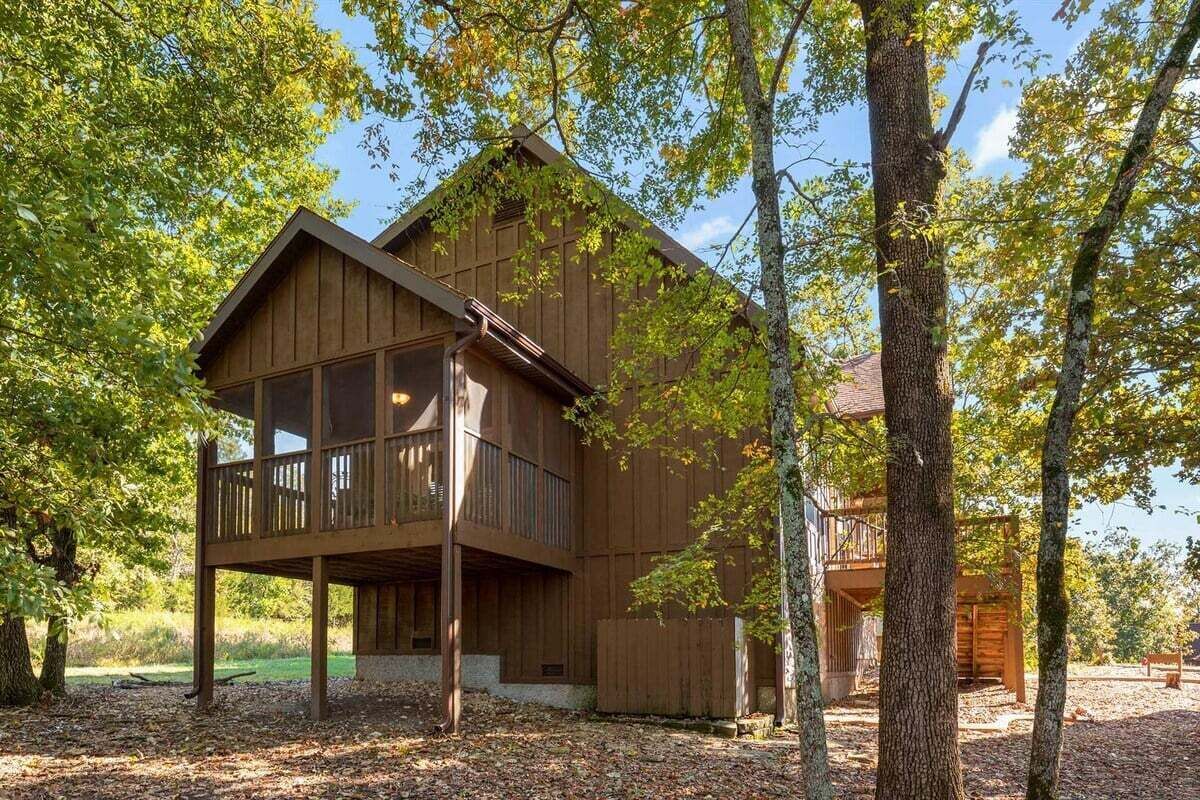 Een houten chalet met een balkon, omringd door bomen.