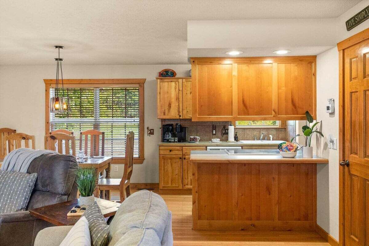 A compact kitchen with wooden cabinets, a central island, and a dining area with a sofa and chairs.