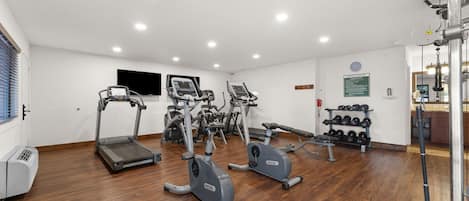 A fitness center with treadmills, elliptical machines, and free weights.