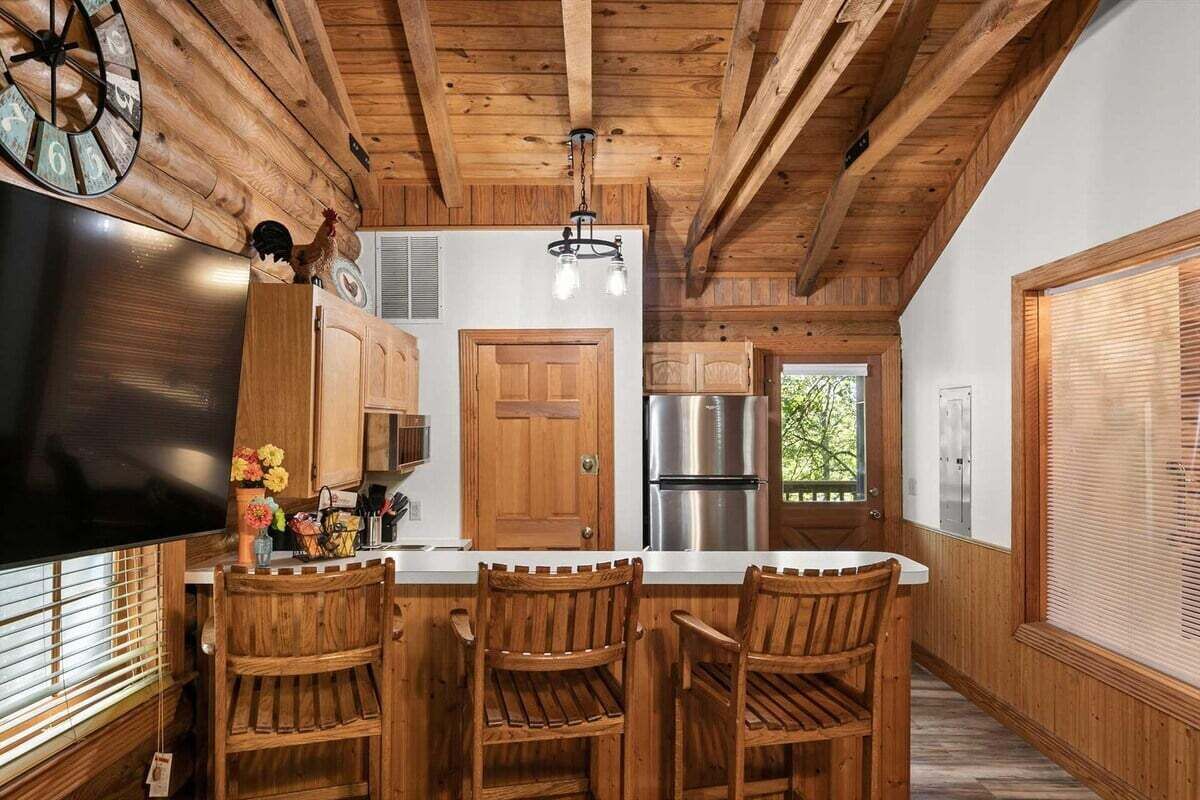 A kitchen with wooden cabinetry, a stainless steel refrigerator, and a wooden island with bar stools.