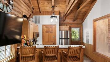 A kitchen with wooden cabinetry, a stainless steel refrigerator, and a wooden island with bar stools.