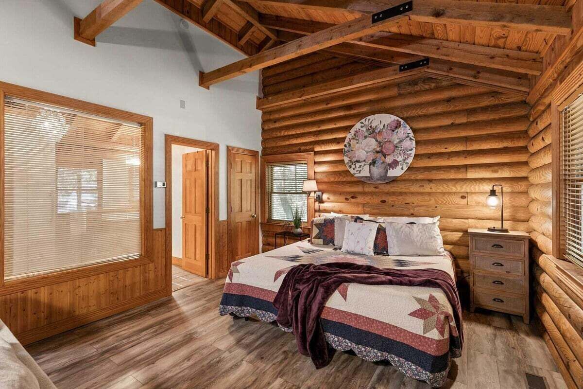 A log cabin bedroom with a bed, bedside table, and a wall-mounted clock.