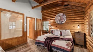 A log cabin bedroom with a bed, bedside table, and a wall-mounted clock.
