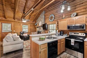 A log cabin interior with a kitchen, dining area, and living room. - Genuine Log Cabin, Jetted Tub, Gas Fireplace, Cmty Pools (Branson)