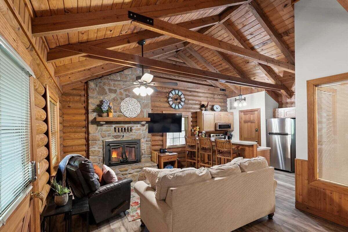 L’intérieur d’une cabane en rondins comprend une cheminée, un téléviseur, un coin repas et une cuisine.