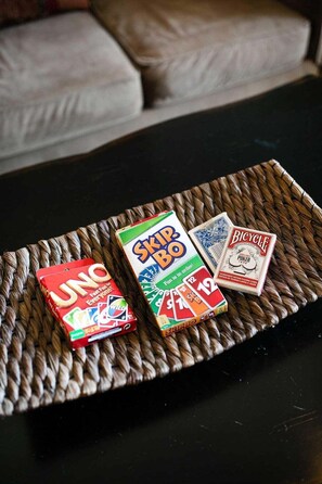 Een gevlochten dienblad met drie gezelschapsspellen: UNO, Skip-Bo en Bicycle Poker.