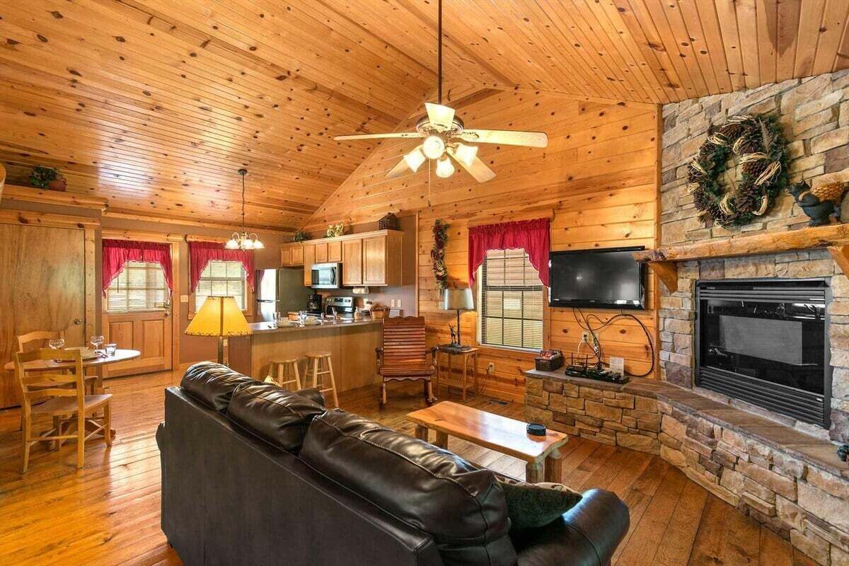 L’intérieur d’une cabane en rondins, avec une cheminée, un plafond en bois et un canapé en cuir.