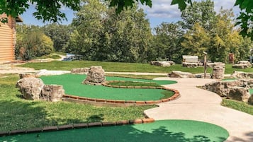A miniature golf course with a winding path, green artificial turf, and scattered rocks.