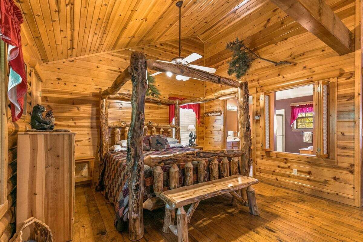 Een kamer met een slaapkamer met baldakijn, houten wanden en een raam met gordijnen.