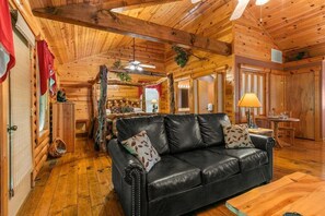 A log cabin interior with a leather sofa, wooden flooring, and a dining area. - Luxury Log Cabin! King Bed, Full Kitchen, Fireplac (Branson)