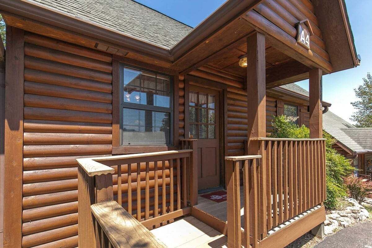 Een houten blokhut met een houten veranda, een deur en een raam.