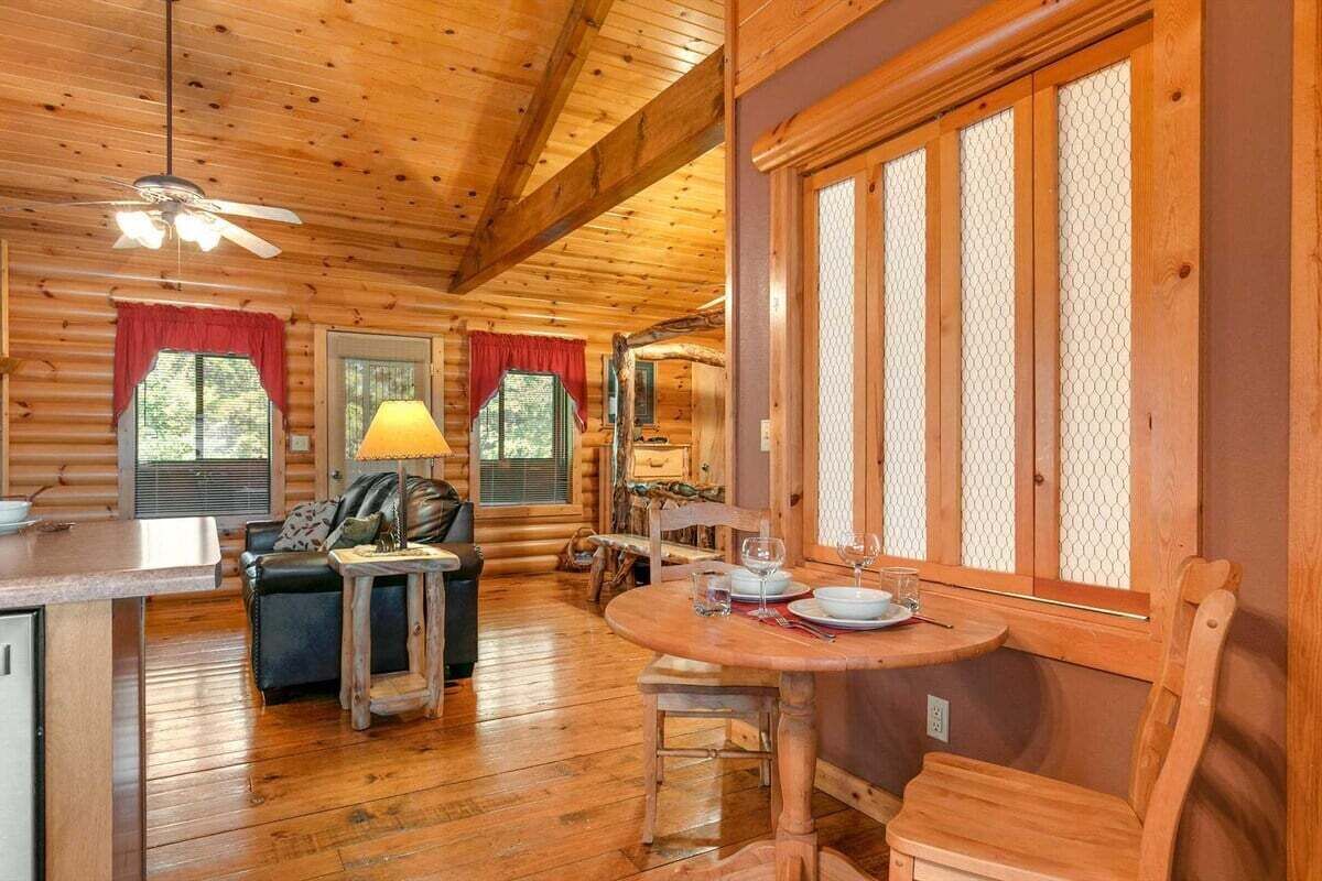 Ein Holzblockhaus-Interieur mit Essbereich, einer Couch und einem Deckenventilator.