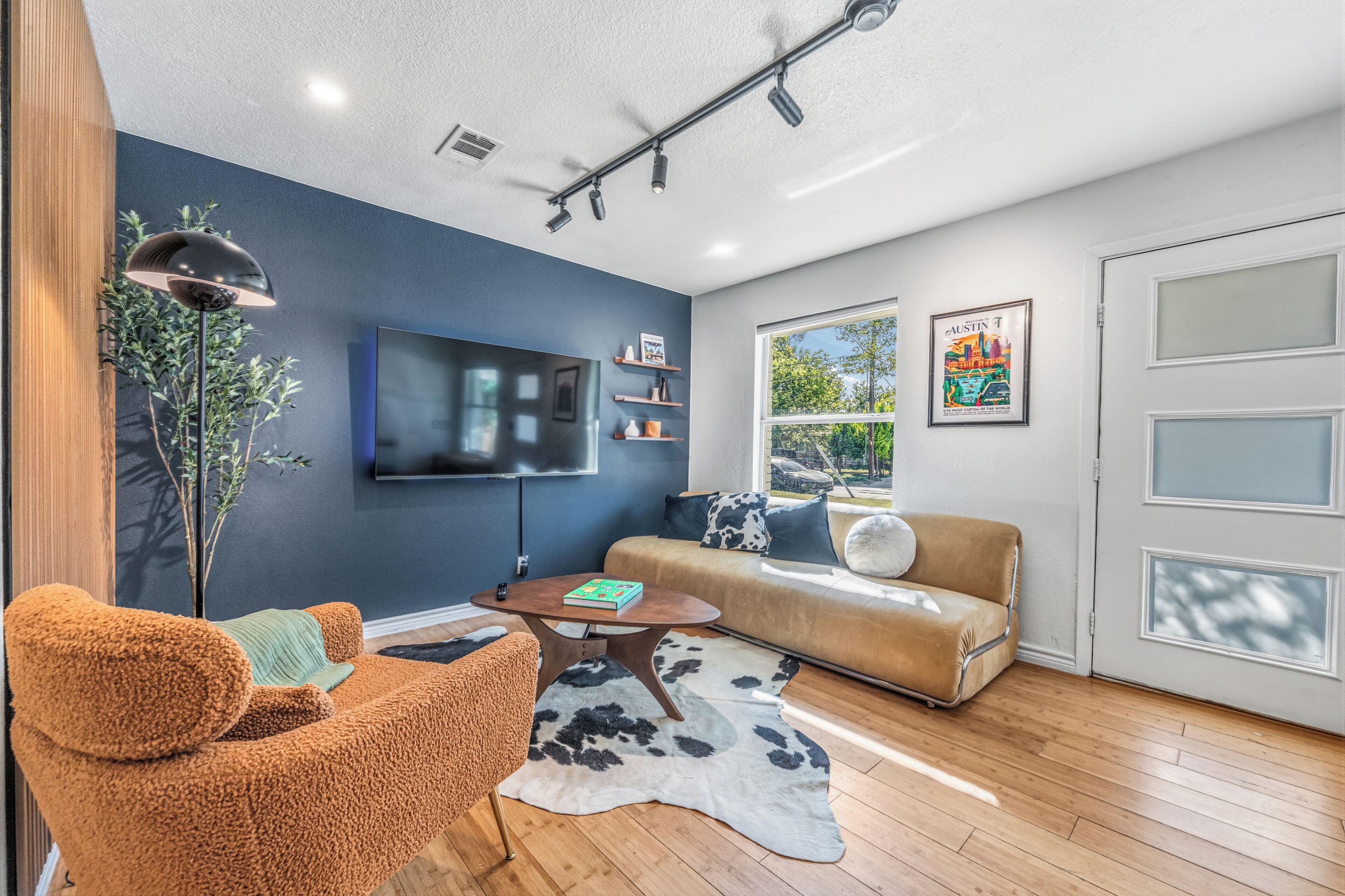 A modern living room with a flat-screen TV, a sofa, a coffee table, and a large window.