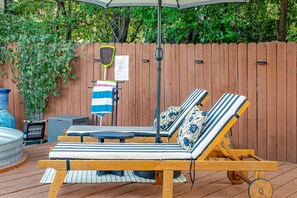 Een houten terras met twee lounge fauteuils, een tafel en een barbecue.