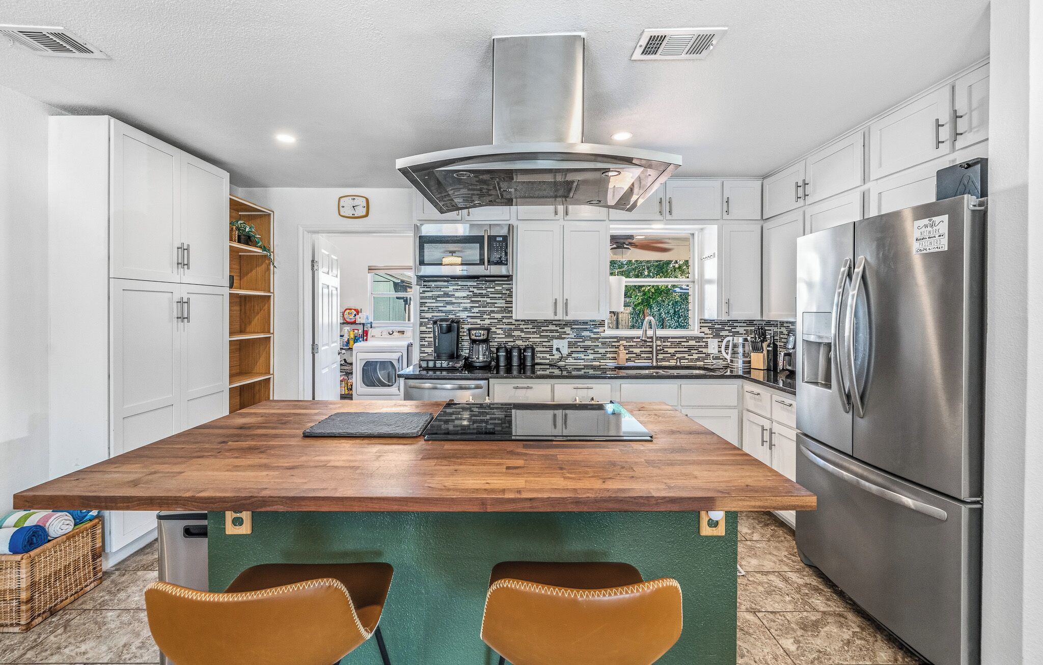 A modern kitchen with a central island, stainless steel appliances, and white cabinetry.