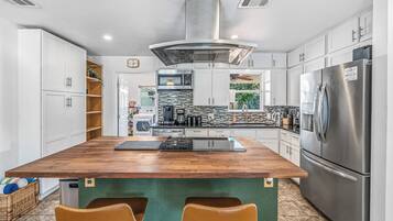 A modern kitchen with a central island, stainless steel appliances, and white cabinetry.