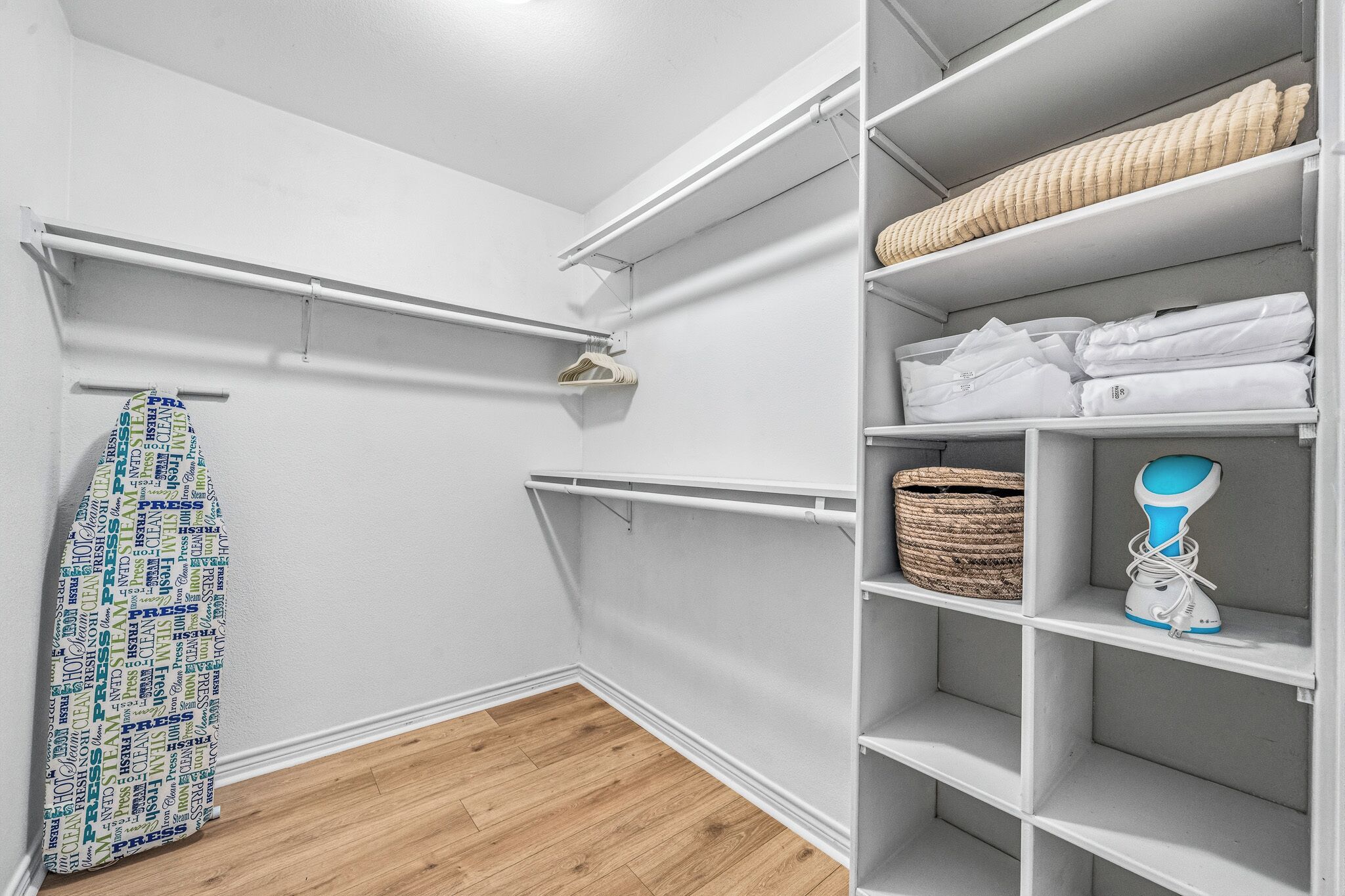 A walk-in closet with white shelving, a hanging rack, and a basket.