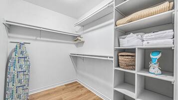 A walk-in closet with white shelving, a hanging rack, and a basket.