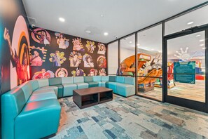 A modern lounge area with a curved blue sofa, a wooden coffee table, and a wall adorned with colorful posters. - Resort Family Cabin_Incredible Amenities_Free Daily Attraction Tickets (Branson)