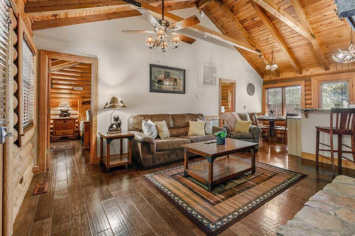 Un vaste espace de vie doté d’un plafond en bois, d’un canapé, d’une table basse et d’une table à manger.