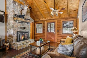 A log cabin interior with a stone fireplace, wooden ceiling, and a cozy seating area. - Incredible Double King Suite Cabin w Amazing Shared Amenities and Free Daily Attraction Tickets! (Branson)