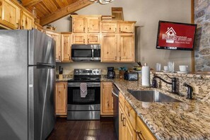 Eine Küche mit Holzschränken, Edelstahlgeräten, Granit-Arbeitsplatten und einer Küchenrückwand aus Stein.