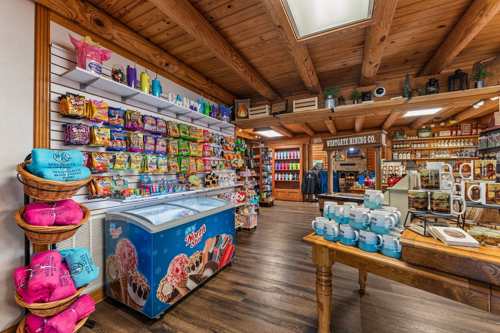 Un magasin dont les étagères sont remplies d’en-cas, où l’on peut voir une variété de pots de crème glacée, et où est affiché un panneau indiquant « Westgate Mining Co. »