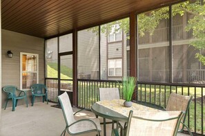 Un patio techado con mesa y sillas, una planta en maceta y vista a una zona residencial.