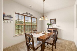 A dining area with a wooden table, chairs, a chandelier, a window with blinds, and a decorative wall piece. - StoneBridge Villa-Near Silver Dollar City-Golf Course Views- Free Daily Attraction Tickets (Branson West)